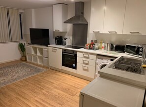 Eine moderne Küche mit weißen Schränken, einem Backofen, einer Mikrowelle, einer Kaffeemaschine und einem Spülbecken.