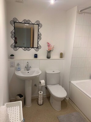 Een badkamer met een wastafel op voetstuk, toilet en bad.