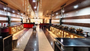 A long, well-lit corridor with a central red counter, flanked by tables with decorative items. - HOTEL DREAM PALACE (Basai)