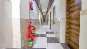 A hotel hallway with a checkered floor, a fire extinguisher, a wooden door with the number 309, and a floral arrangement. - HOTEL DREAM PALACE (Basai)