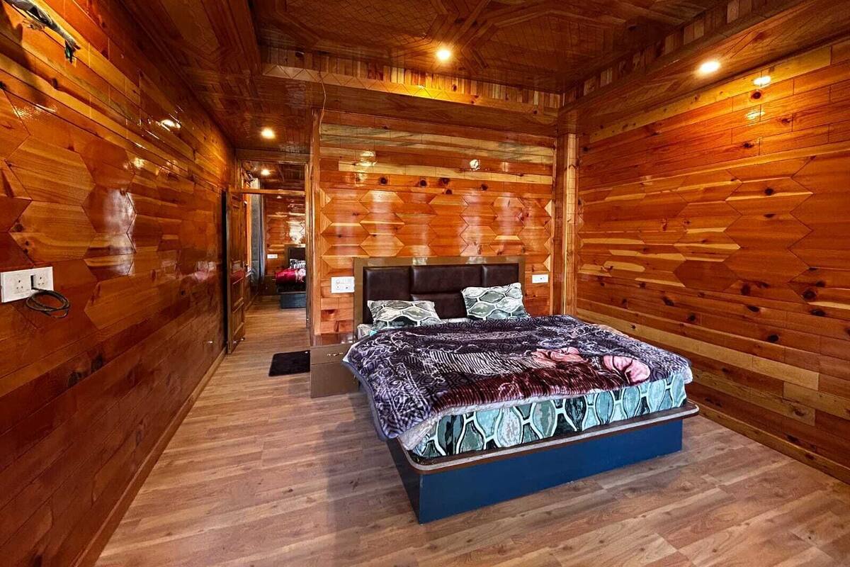 A wooden interior with a bed, a visible electrical outlet, and a ceiling light.
