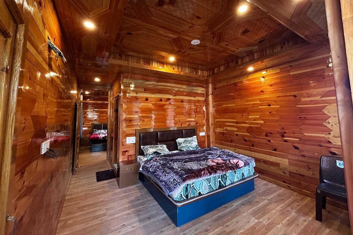 A wooden cabin bedroom with a bed, a dresser, and a chair.