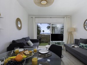 Ein modernes Wohnzimmer mit Essbereich, einem Flachbildfernseher und Blick auf den Strand.