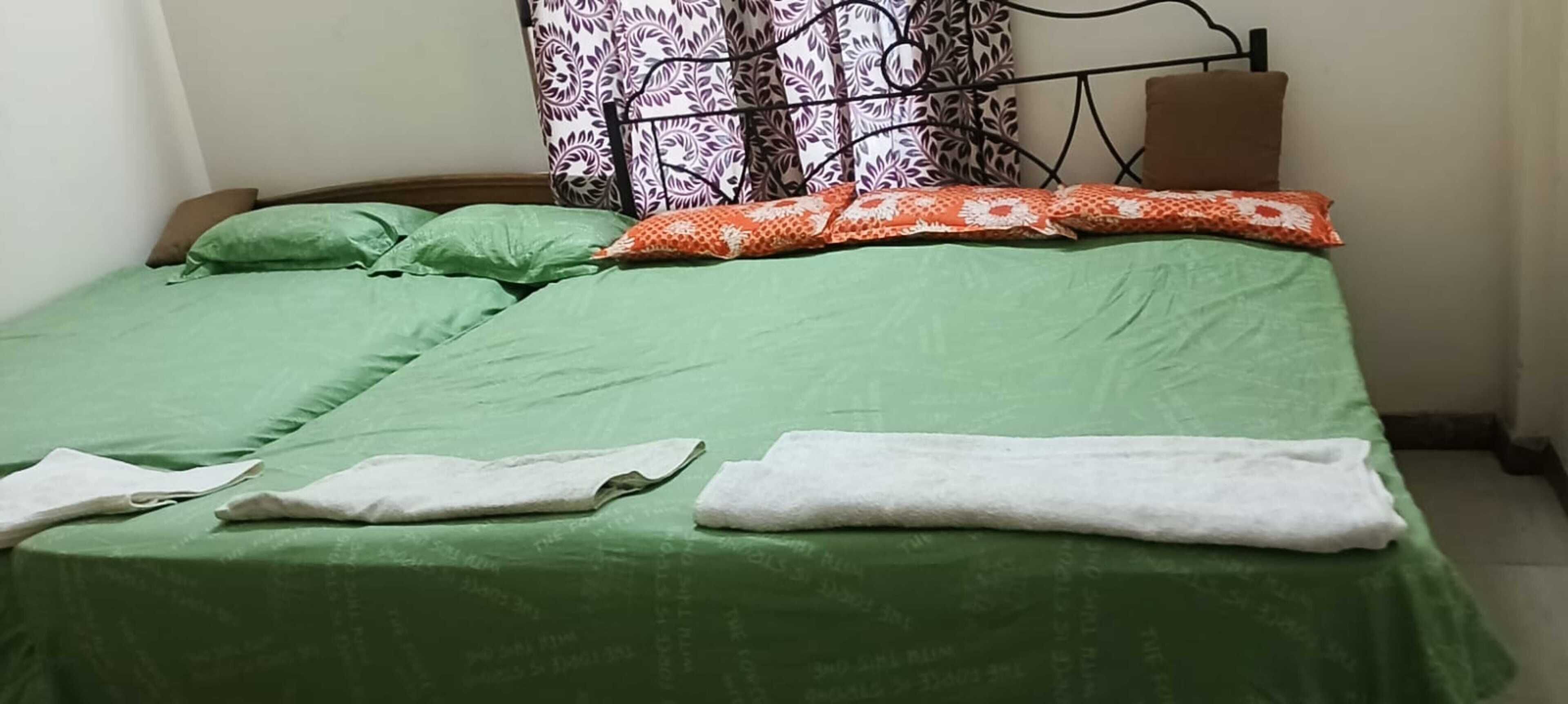 Een bed met groen beddengoed, kussens en een dekbed.