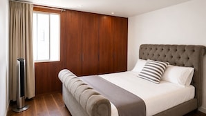 Une chambre avec un grand lit, une armoire en bois et une fenêtre avec des rideaux.