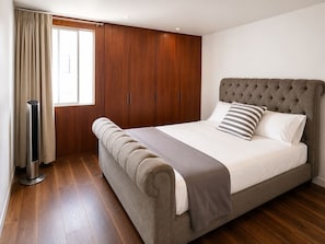 Ein Schlafzimmer mit einem großen Bett, einem Holzschrank und einem Fenster mit Vorhängen.