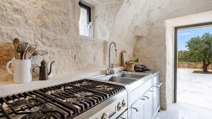 Eine Küche mit Gasherd, Spüle und Steinwänden.