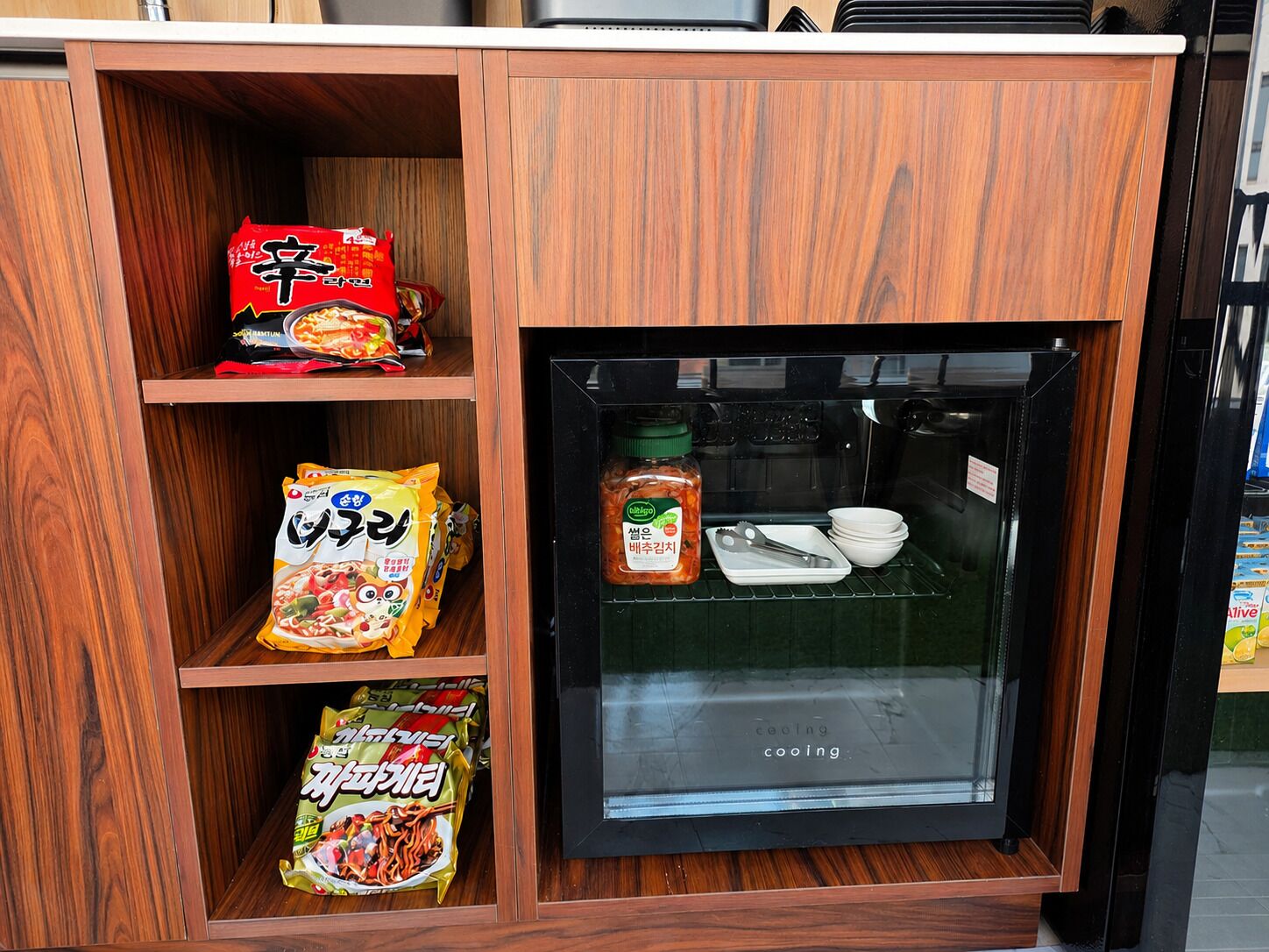A refrigerator with a glass door, containing condiments and utensils.