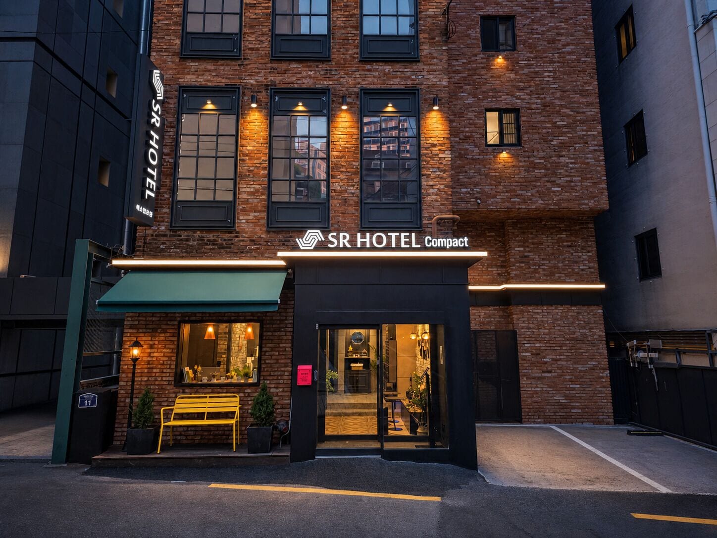 Un hôtel de taille modeste, doté d’une façade en briques, de grandes fenêtres et d’un auvent vert.