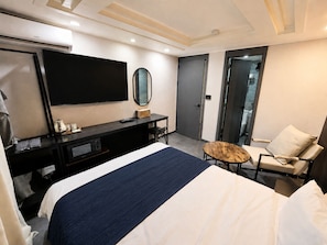Una habitación de hotel con cama, escritorio, silla, televisor y puerta.