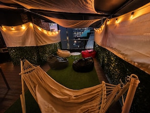 A rooftop terrace with a hammock, bean bags, and string lights.