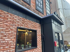 Un hotel con fachada de ladrillo, una ventana con lámpara colgante y un cartel sobre la entrada.