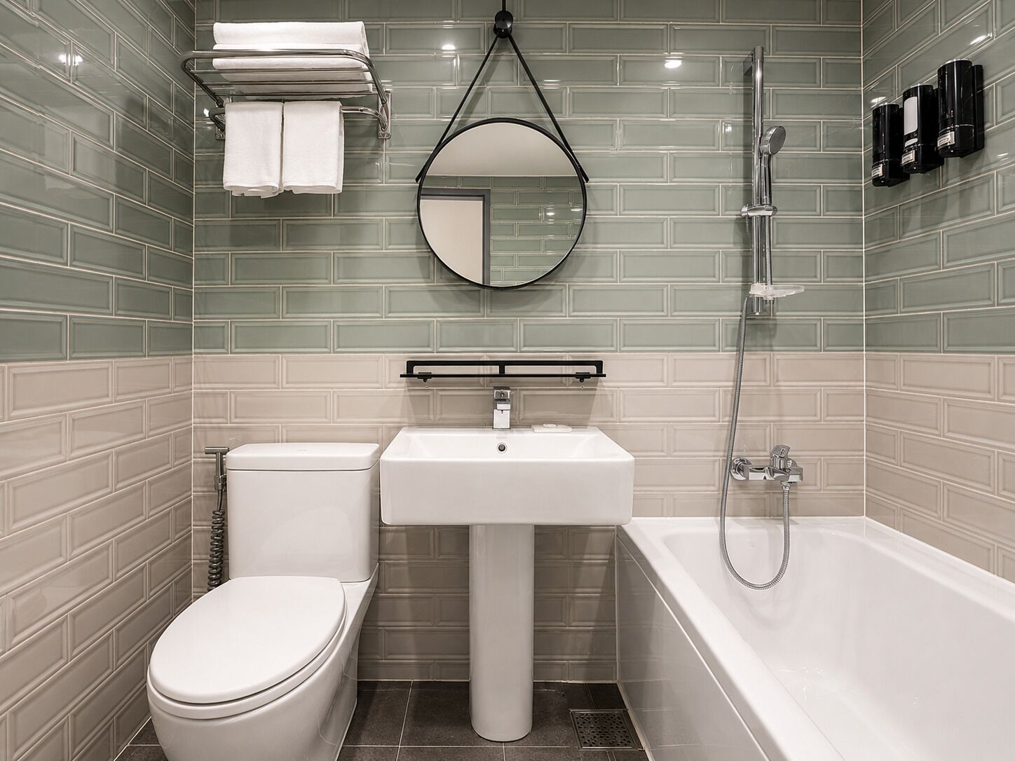A bathroom with a toilet, sink, and bathtub, with a mirror above the sink and a towel rack above the toilet.