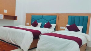 Two beds with headboards, white bedding, and red accents.