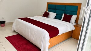 A neatly made bed with a wooden frame and a teal headboard, a red and white striped blanket, and a red throw pillow.