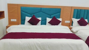A hotel room with two beds, a wooden headboard, and a teal accent wall.