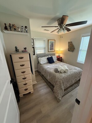 A bedroom with a bed, a ceiling fan, a dresser, and a window with blinds. - Charming 2-Bedroom House - 1 mile from Mercedes Benz Stadium (Atlanta)