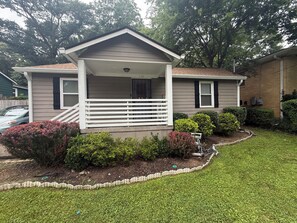 A single-story house with a front porch, a mailbox, and a small garden area. - Charming 2-Bedroom House - 1 mile from Mercedes Benz Stadium (Atlanta)