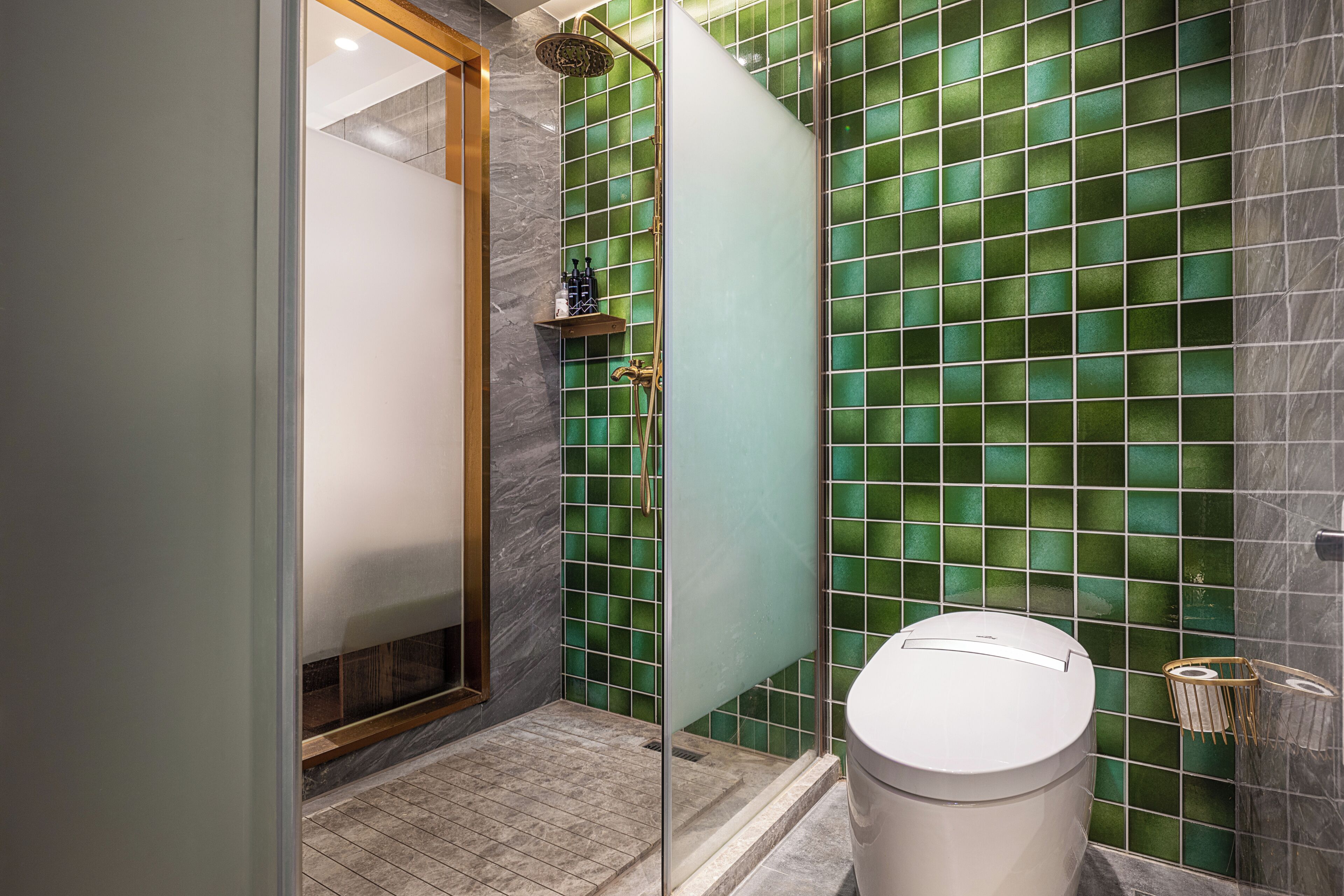 Une salle de bain avec une douche à parois de verre, des toilettes et un mur recouvert de carreaux de marbre.