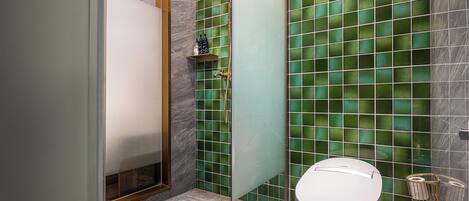 Une salle de bain avec une douche à parois de verre, des toilettes et un mur recouvert de carreaux de marbre.