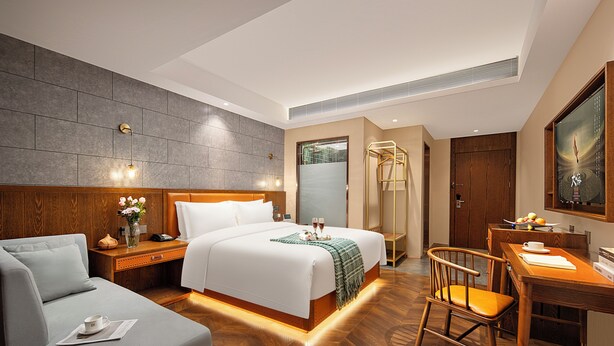 A hotel room with a large bed, a desk, a chair, and a small sofa. - Borrman International Hotel Shunyi (Shunyi)