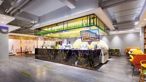 A fitness center with a reception desk, seating area, and a large screen displaying a building. - Borrman International Hotel Shunyi (Shunyi)