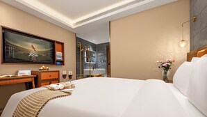 A hotel room with a large bed, a desk with a computer, a TV, and a vase with flowers. - Borrman International Hotel Shunyi (Shunyi)