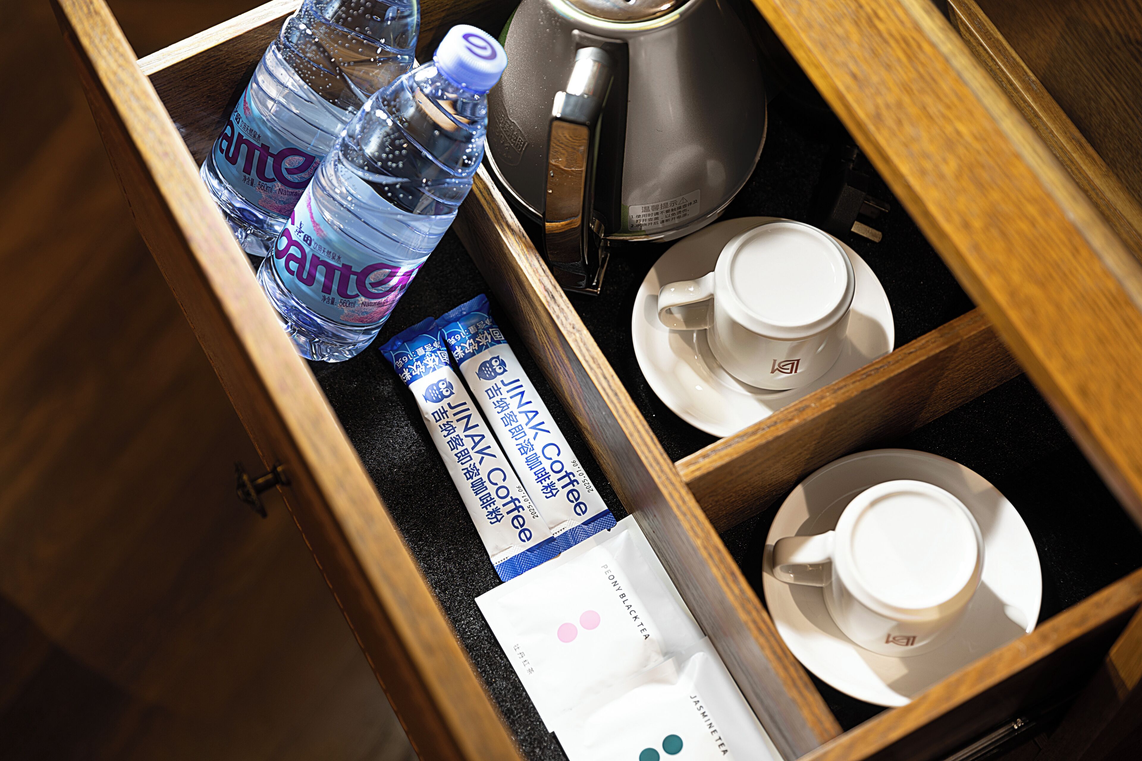 Un tiroir contenant une machine à café, des bouteilles d’eau et des sachets de thé.