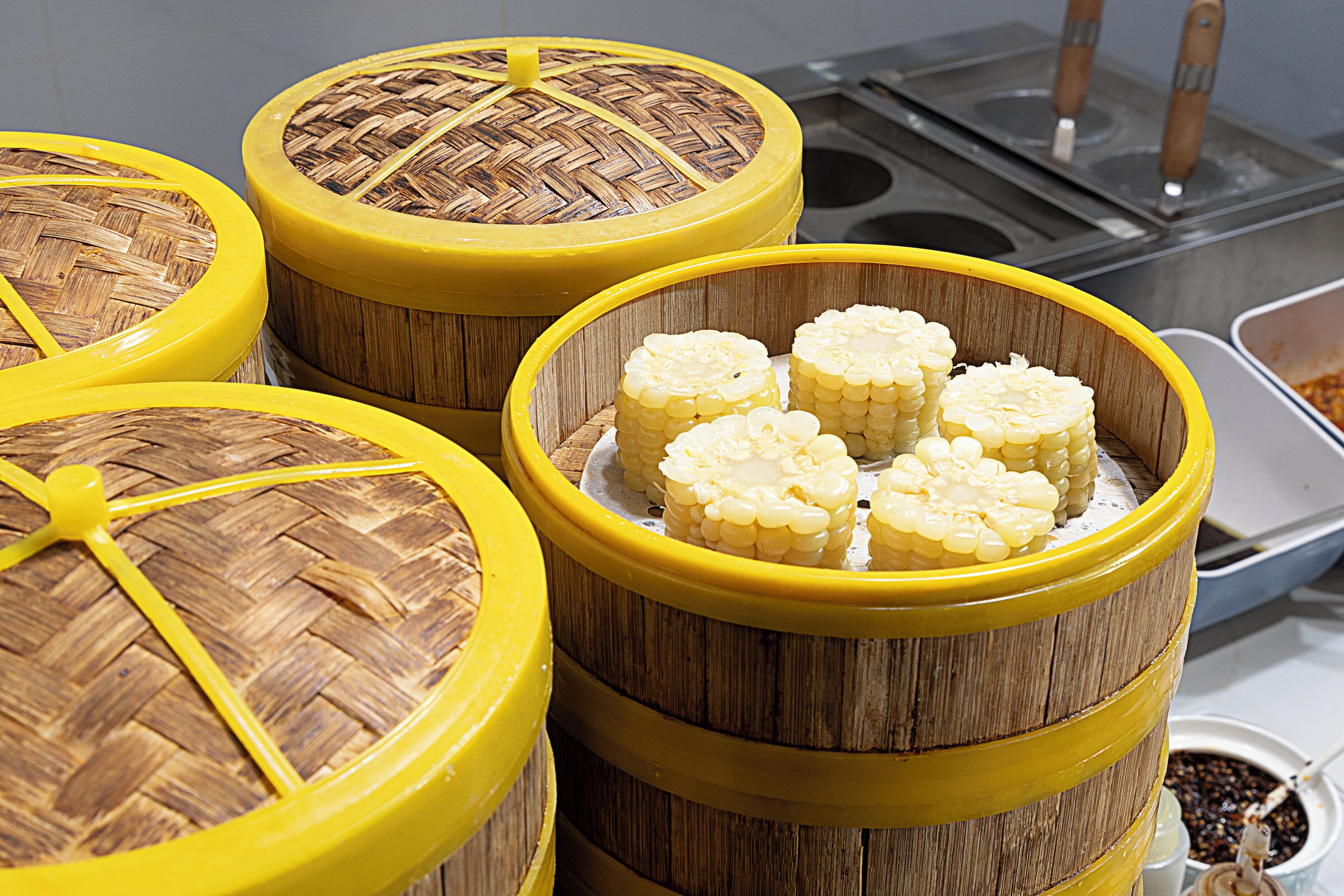 A set of yellow and brown woven containers with corn cobs inside.