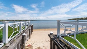 A waterfront walkway with white railings and a sandy beach. - Hampton Bays Townhouse - Pool, Beach Access (Hampton Bays)