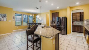 A kitchen with a granite countertop, stainless steel refrigerator, and yellow walls. - Alamo Heights Haven+15 min 2 Seaworld+Pet Friendly (San Antonio)