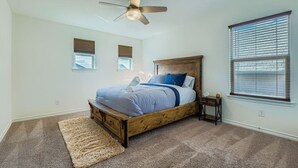 A bedroom with a wooden bed, a ceiling fan, a window with blinds, and a small bedside table. - Alamo Heights Haven+15 min 2 Seaworld+Pet Friendly (San Antonio)