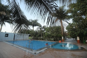 A swimming pool with a diving board, surrounded by palm trees and a tiled deck. - The Kiaan Hotels and Resort (Mendarda)
