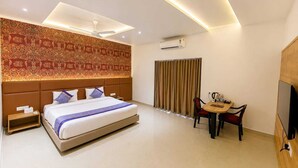 Une chambre d’hôtel avec un grand lit, un bureau avec une chaise, un appareil de climatisation et un téléviseur.