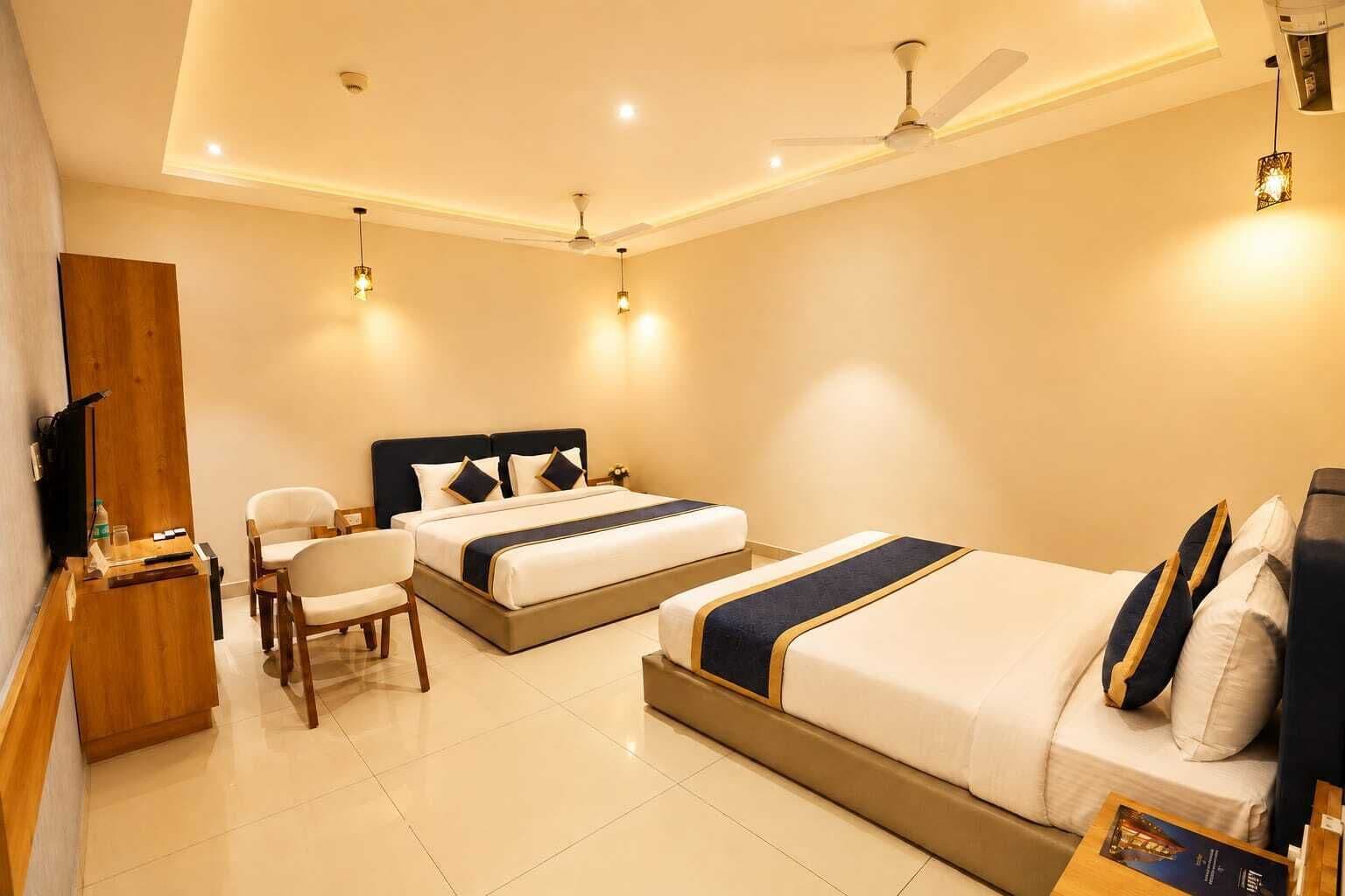 A hotel room with a large bed, a smaller bed, a desk with a chair, and a television.