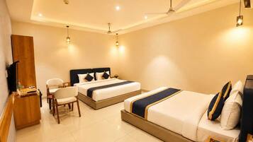 A hotel room with a large bed, a smaller bed, a desk with a chair, and a television.