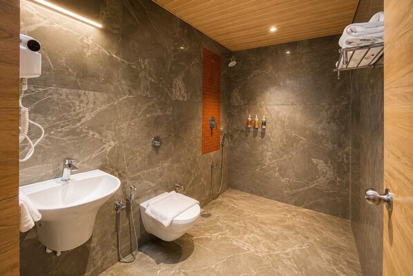 Un baño moderno con piso de mármol, un lavamanos, un inodoro y una zona de ducha.