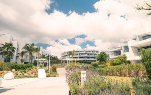 A modern hotel with a central courtyard, surrounded by lush greenery and palm trees. - Exclusive Two-Bed Coastal Apartment in Pure South (Manilva)