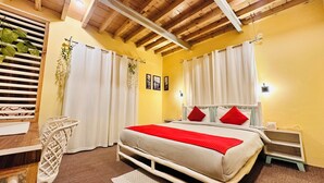 Une chambre à coucher avec un lit, des rideaux blancs, un plafond en bois, une table de chevet et une commode.