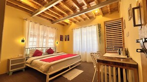 Une chambre à coucher avec un lit, une table de chevet, une chaise et une fenêtre avec des rideaux.