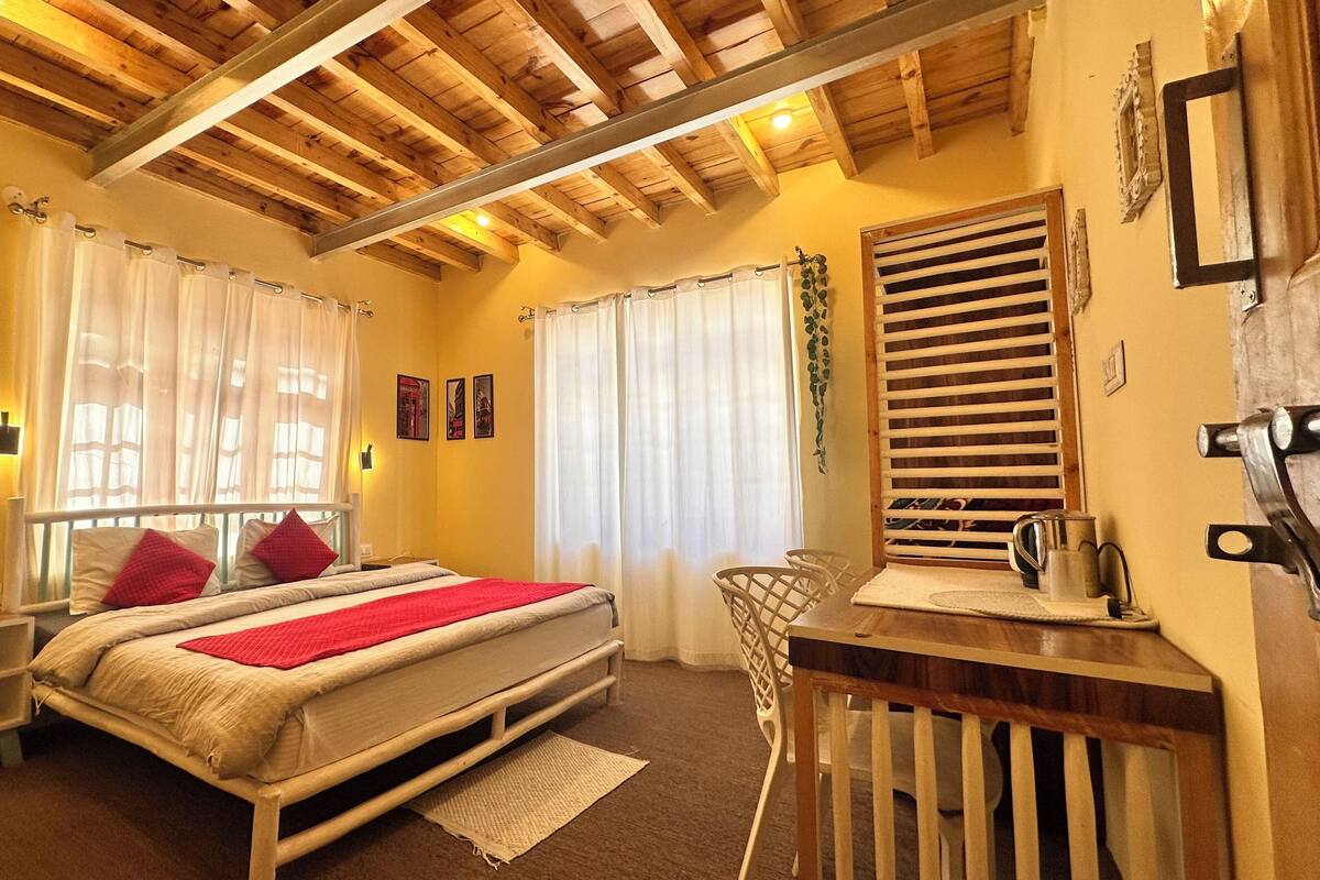 A bedroom with a bed, bedside table, chair, and a window with curtains.