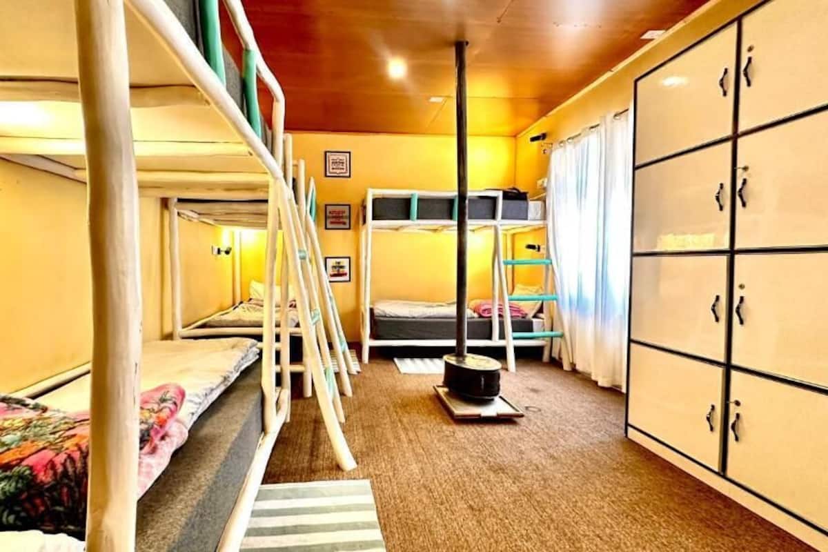 A bunk bed room with a wooden ceiling, a wardrobe, and a small table.