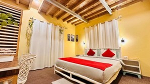 Une chambre à coucher avec un lit, des rideaux blancs, une table de chevet, une commode, un plafond en bois et une fenêtre avec des stores.