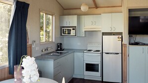 A compact kitchen with a sink, microwave, stove, and refrigerator.