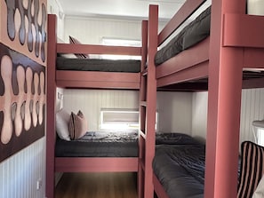 A bunk bed room with a window, a radiator, and a wall with a unique pattern.