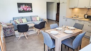 Moderni keittiö, jossa on ruokailutila, sohva ja seinällä taulu.