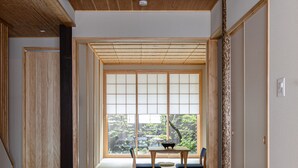 Et traditionelt japansk rum med tatamimåtter, en skydedør og udsigt gennem en shoji-skærm.