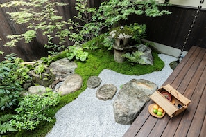 A wooden deck with a stone garden, a wooden bench, and a wicker picnic basket with fruits. - Kyoran [6 min. by cab from Kyoto Stn.] Max. 6 people｜Renovation in 2025｜Private use of a machiya in a quiet alleyway｜Nishi Honganji temple nearby (京都市)
