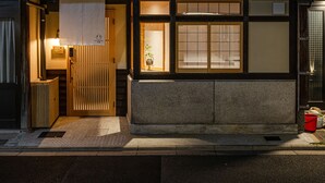 En traditionel japansk bygning med en træbalkon og en oplyst indgang.