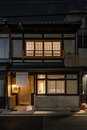A traditional Japanese building with a wooden balcony and a lit entrance. - Kyoran [6 min. by cab from Kyoto Stn.] Max. 6 people｜Renovation in 2025｜Private use of a machiya in a quiet alleyway｜Nishi Honganji temple nearby (京都市)